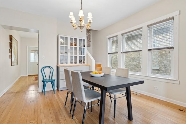 dining room featuring light wood-style flooring, an inviting chandelier, baseboards, and visible vents