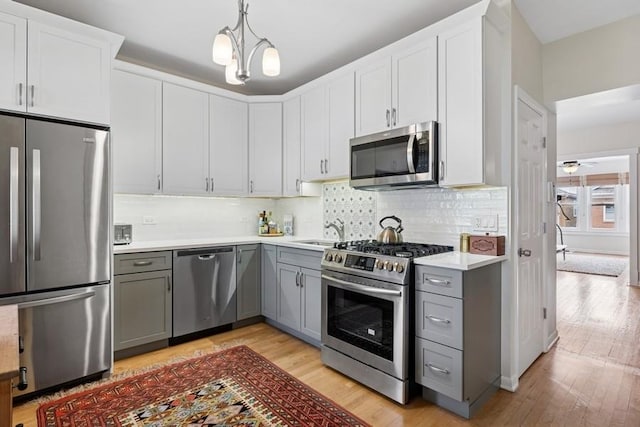 kitchen with gray cabinets, appliances with stainless steel finishes, light countertops, and light wood-style flooring