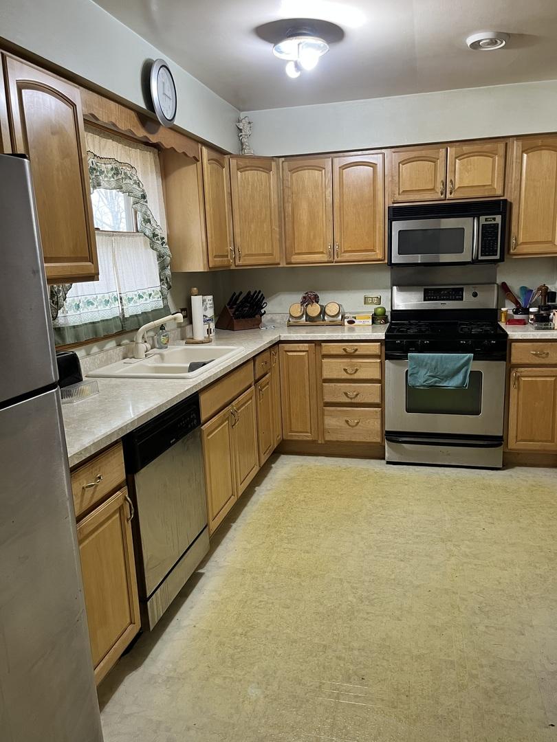 kitchen with brown cabinets, appliances with stainless steel finishes, light countertops, and a sink