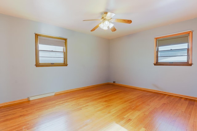 spare room featuring baseboards, baseboard heating, a ceiling fan, and light wood-style floors