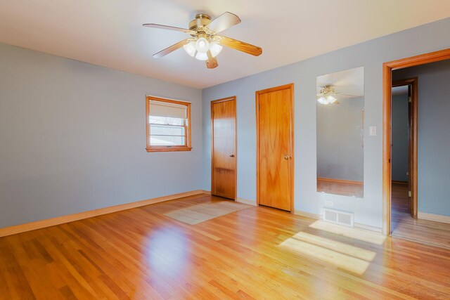 unfurnished bedroom featuring light wood finished floors, multiple closets, visible vents, ceiling fan, and baseboards