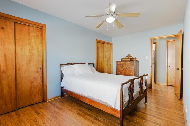 bedroom with multiple closets, light wood-type flooring, ceiling fan, and baseboards