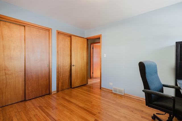 unfurnished office with light wood-style flooring, visible vents, and baseboards