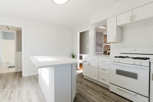 kitchen featuring light wood-style floors, white cabinetry, light countertops, and white gas stove