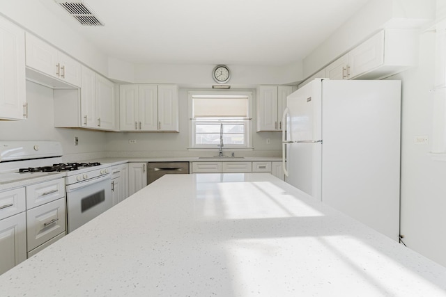 kitchen with white appliances, visible vents, white cabinets, light stone countertops, and a sink