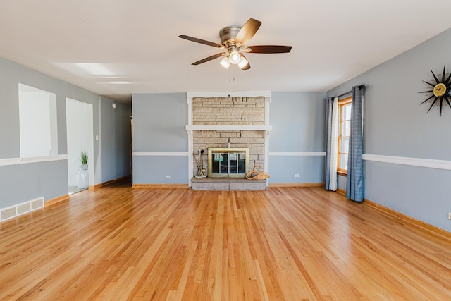 unfurnished living room featuring a fireplace, visible vents, a ceiling fan, wood finished floors, and baseboards