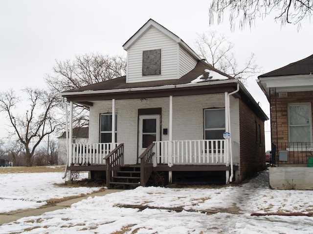 bungalow-style home with covered porch and brick siding