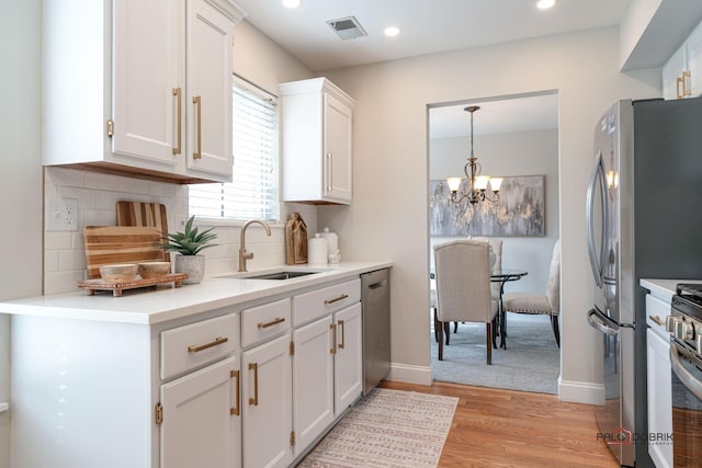 kitchen with a sink, visible vents, white cabinets, appliances with stainless steel finishes, and light wood finished floors