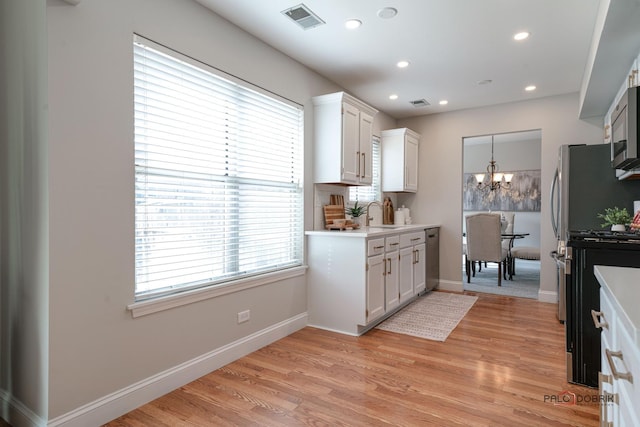 kitchen with visible vents, appliances with stainless steel finishes, light countertops, light wood-type flooring, and a chandelier