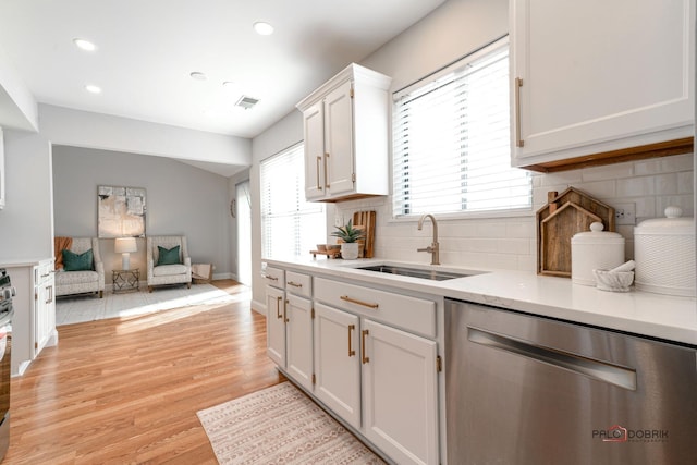 kitchen featuring visible vents, dishwasher, light wood-style flooring, light countertops, and a sink