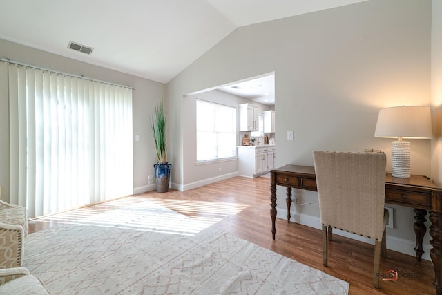 office with vaulted ceiling, light wood-type flooring, visible vents, and baseboards