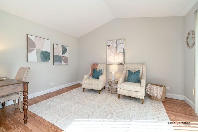 sitting room with baseboards, vaulted ceiling, and wood finished floors