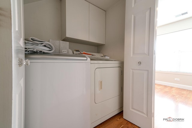 laundry room featuring cabinet space, light wood-style flooring, visible vents, and washer and dryer