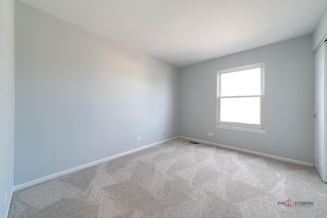 empty room featuring baseboards, visible vents, and light colored carpet