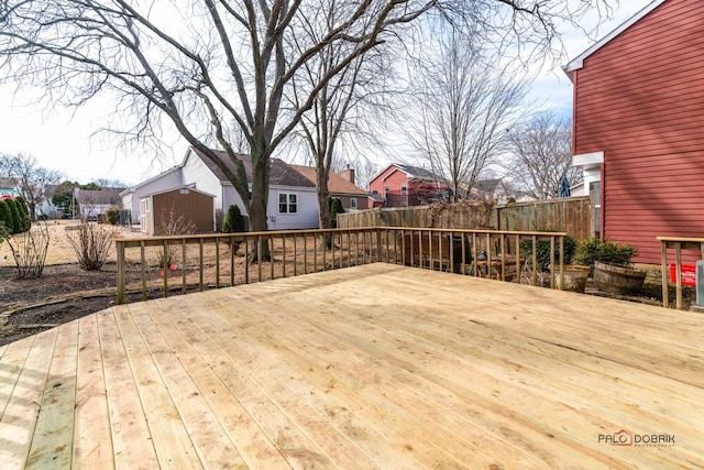 deck featuring an outbuilding, a shed, fence, and a residential view