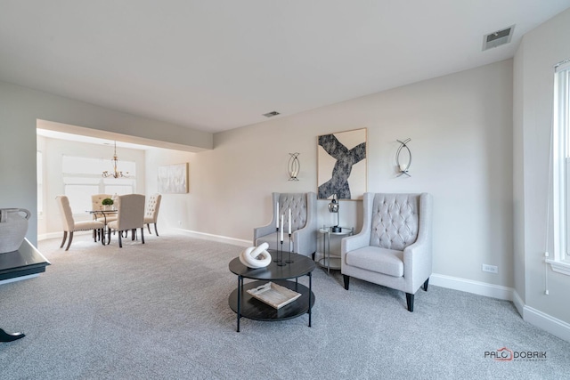 living area featuring a notable chandelier, carpet floors, visible vents, and baseboards