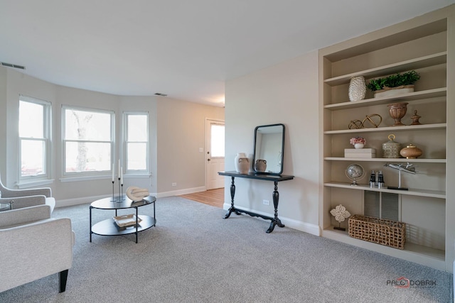 living area with built in features, carpet, visible vents, and baseboards