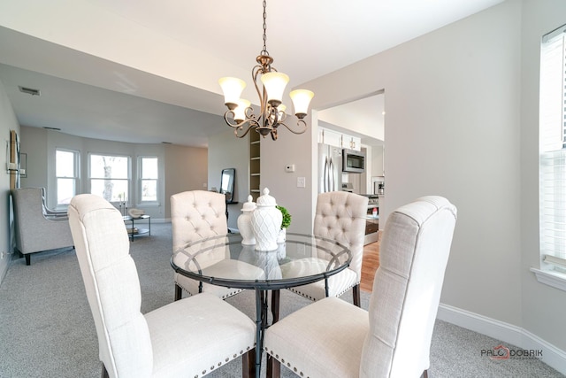 dining room with baseboards, a notable chandelier, and light colored carpet