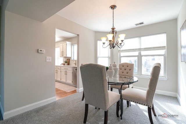 dining space with visible vents, a notable chandelier, light carpet, and baseboards