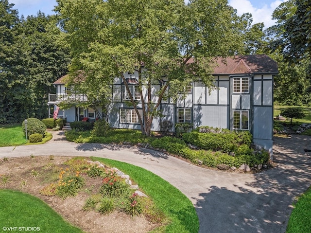 tudor house with driveway and a balcony