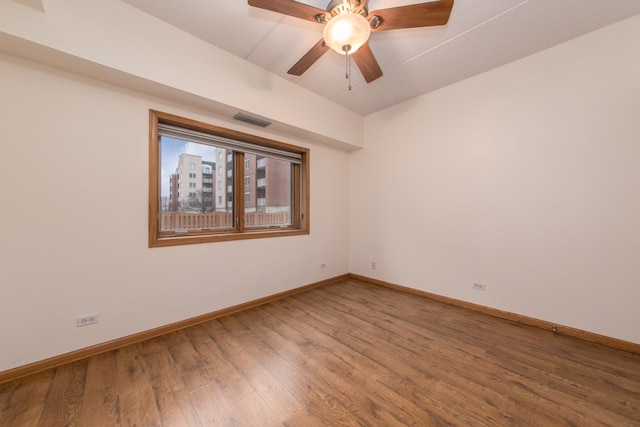 spare room featuring ceiling fan, wood finished floors, visible vents, and baseboards