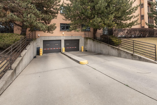 garage featuring fence and concrete driveway