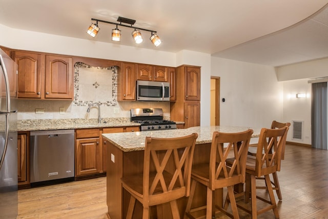 kitchen featuring appliances with stainless steel finishes, light wood-type flooring, a sink, and visible vents