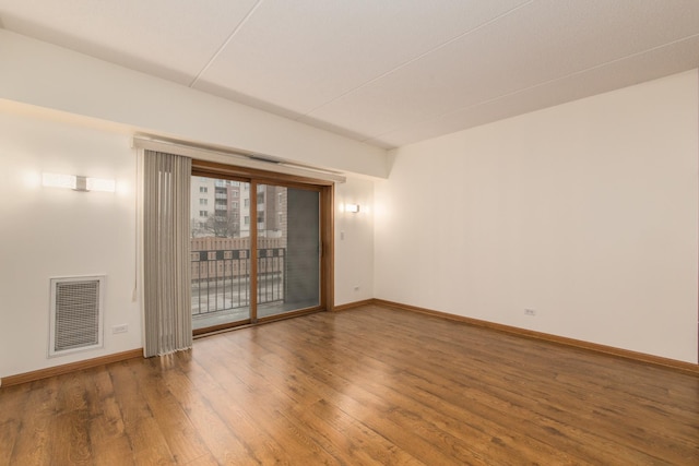 spare room featuring baseboards, visible vents, and wood finished floors