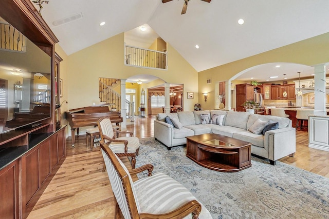 living area with light wood-type flooring, ornate columns, arched walkways, and a ceiling fan