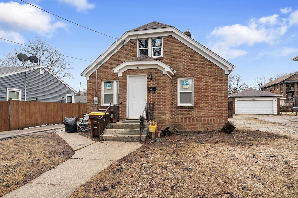 bungalow with brick siding, an outdoor structure, fence, and a detached garage