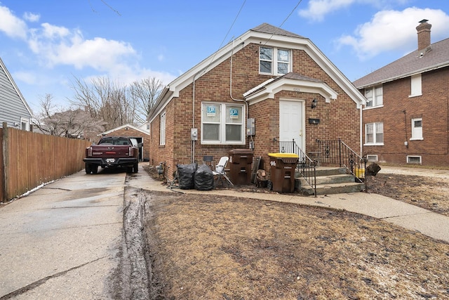 view of front of home with fence, concrete driveway, and brick siding