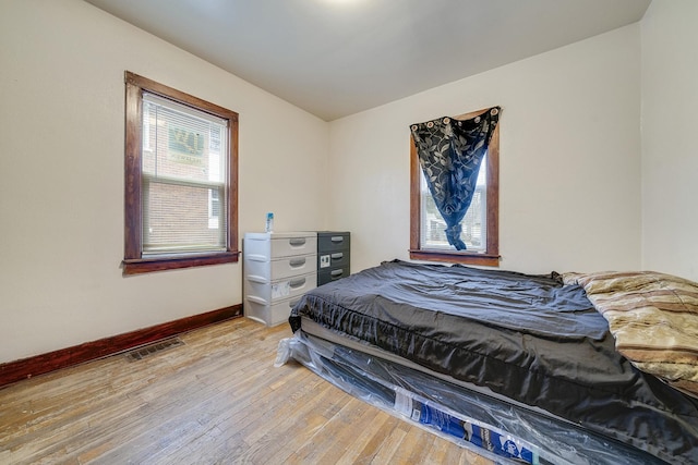 bedroom with light wood-type flooring, baseboards, and visible vents