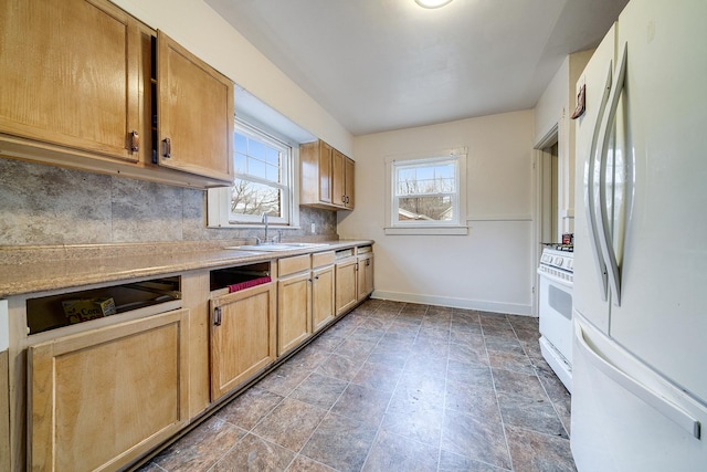 kitchen featuring light countertops, decorative backsplash, a sink, white appliances, and baseboards