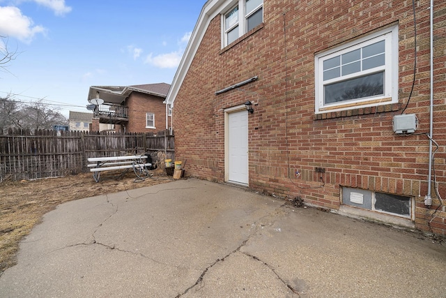 view of home's exterior featuring fence, a patio, and brick siding