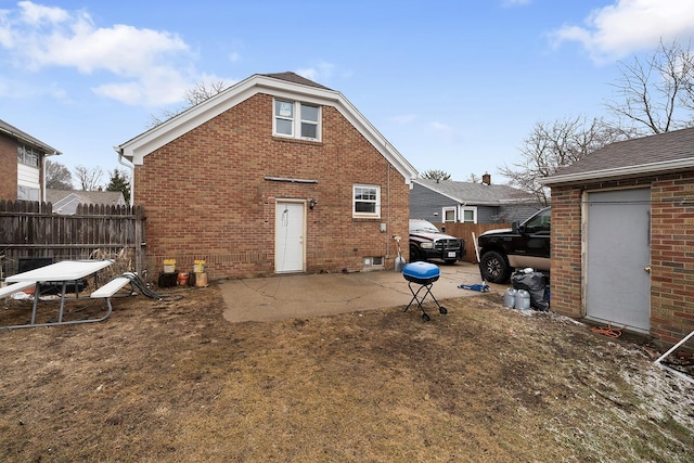 rear view of house with a patio, brick siding, and fence