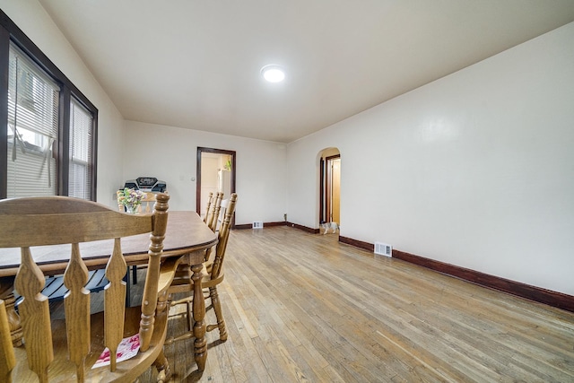 dining area featuring arched walkways, light wood-style flooring, visible vents, and baseboards