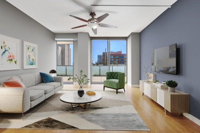 living room with expansive windows, a ceiling fan, and light wood-type flooring