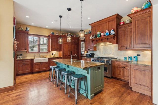 kitchen with a sink, high end range, a kitchen breakfast bar, and wood finished floors