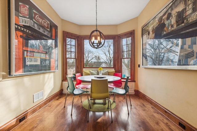 dining space with an inviting chandelier, visible vents, baseboards, and wood finished floors