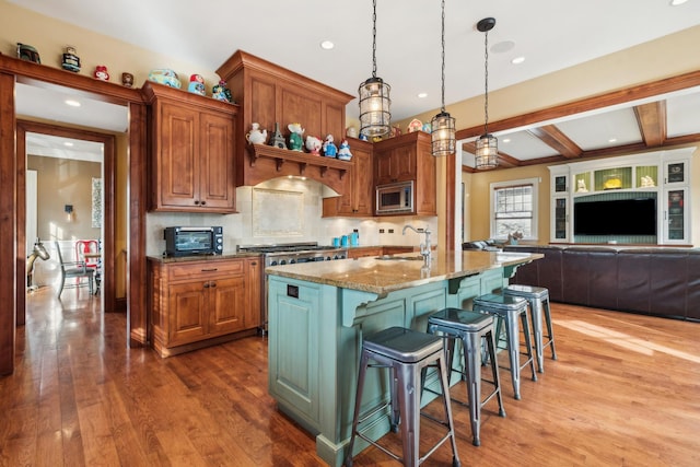 kitchen featuring stone counters, a breakfast bar, stainless steel appliances, a sink, and wood finished floors