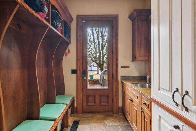 mudroom with stone finish floor and a sink