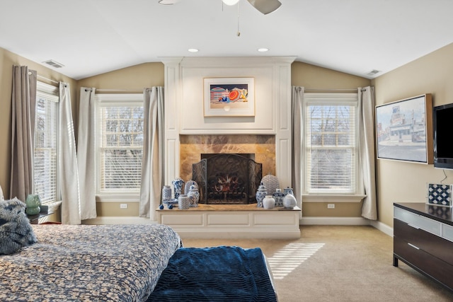 bedroom featuring light carpet, multiple windows, vaulted ceiling, and a tile fireplace