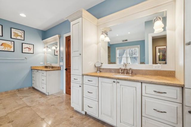 bathroom with two vanities, a sink, visible vents, and baseboards