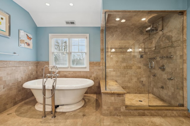 bathroom with visible vents, wainscoting, a freestanding tub, a shower stall, and tile walls