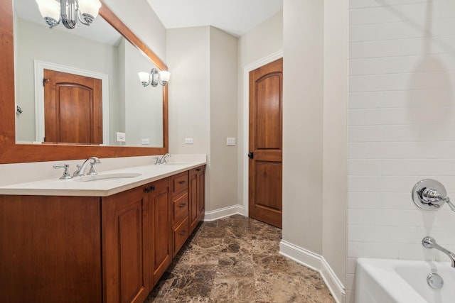 full bathroom with a notable chandelier, double vanity, tub / shower combination, a sink, and baseboards