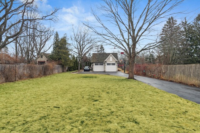 view of yard featuring a garage, fence, and an outbuilding