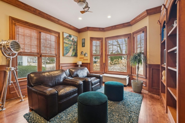 sitting room featuring a ceiling fan, a wainscoted wall, crown molding, light wood-type flooring, and recessed lighting