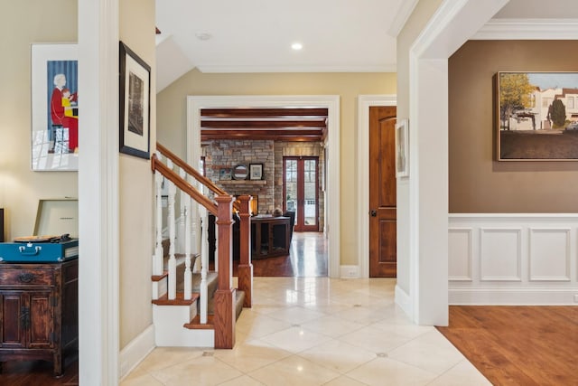 entryway featuring a wainscoted wall, a decorative wall, stairway, ornamental molding, and tile patterned floors