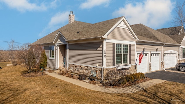 single story home featuring a front lawn, aphalt driveway, a chimney, stone siding, and an attached garage