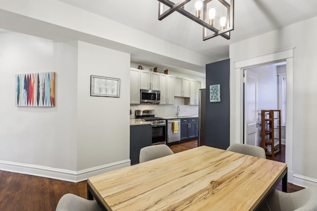 dining room with a notable chandelier, dark wood finished floors, and baseboards